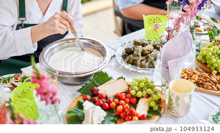 Cut with a knife, separate the serum. Master class and cheese tasting. Women make cheese. The enzyme and starter culture are added to the milk in a metal container. Milk folding process, home 104933124