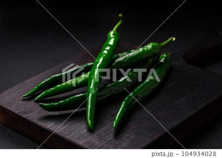 Fresh hot green chili peppers on a dark concrete background 104934028
