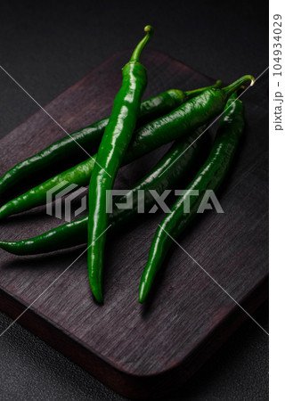 Fresh hot green chili peppers on a dark concrete background 104934029