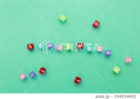 inscription September made by multicolor plastic cubes on a green background. 104934692