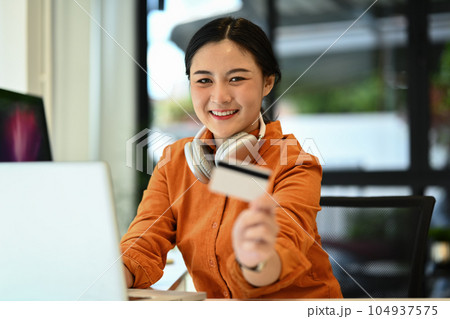 Cheerful young woman holding credit card laptop. E-commerce, banking service and shopping online 104937575