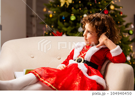 Adorable girl in Christmas dress near the classic decorated christmas tree 104940450