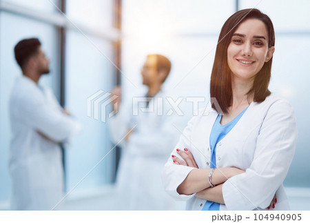 Smiling female doctor in lab coat with arms crossed against 104940905