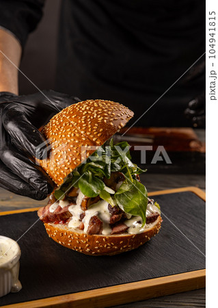 Chef's hand preparing a delicious steak burger Chef's hand preparing a delicious steak burger 104941815