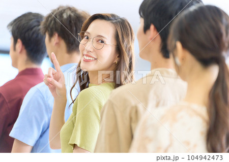列に並びながら振り返って視線を向ける若い女性 列に並びながら振り返って視線を向ける若い女性 104942473