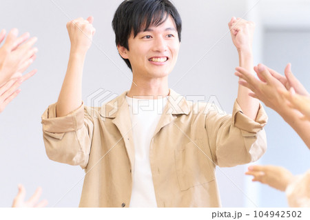 称賛を受けて得意げな表情を見せる若い男性 称賛を受けて得意げな表情を見せる若い男性 104942502