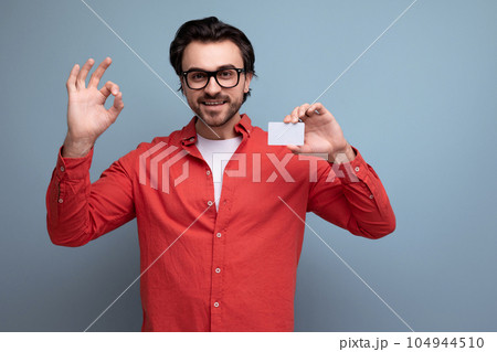 smart handsome young brunette man with glasses advertises a bank card smart handsome young brunette man with glasses advertises a bank card 104944510