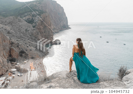 Woman sea trevel green dress. Side view a happy woman with long hair in a long mint dress posing on a beach with calm sea bokeh lights on sunny day. Girl on the nature on blue sky background. 104945732