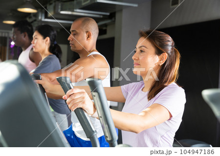 Woman training on elliptical trainer at gym Woman training on elliptical trainer at gym 104947186