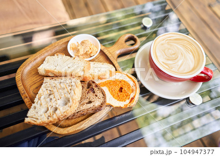 Assorted sliced bread on a wooden board. Served with smoked butter. Breakfast with cappuccino coffee. Composition with butter and bread on wooden plate. Assorted sliced bread on a wooden board. Served with smoked butter. Breakfast with cappuccino coffee. Composition with butter and bread on wooden plate. 104947377