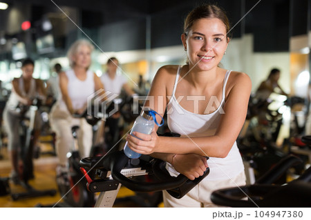 Woman posing near stationary bike in gym 104947380