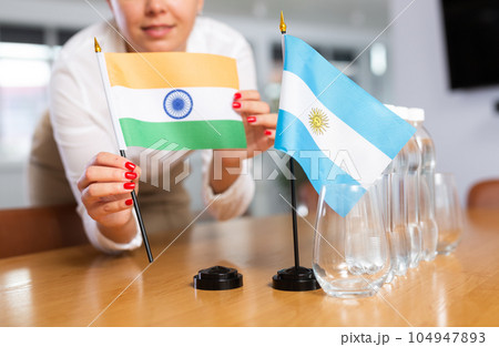 Unrecognizable girl sets midget flags of Argentina and India before international negotiations Unrecognizable girl sets midget flags of Argentina and India before international negotiations 104947893