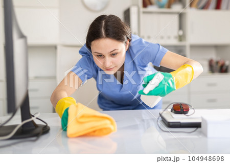 Cleaning company employee wipes dust from table Cleaning company employee wipes dust from table 104948698