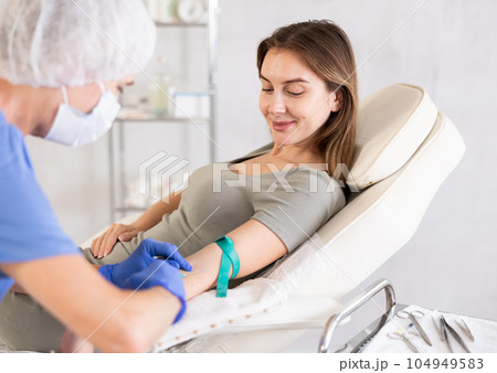 Elderly doctor drawing blood from young patient. 104949583