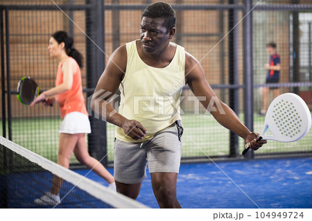 African american paddle tennis player preparing to hit ball on court 104949724