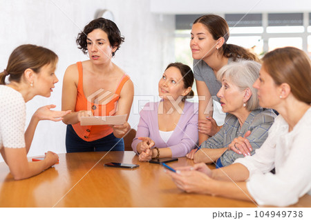 Group of people of different ages sitting around table and communicating 104949738