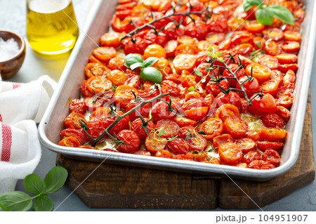 Cherry tomatoes roasted with garlic and spices on a tray 104951907