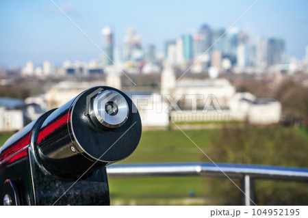 Lookout telescope monocular with blurred Canary Wharf district in London at distance Lookout telescope monocular with blurred Canary Wharf district in London at distance 104952195
