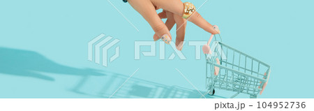Beautiful groomed womans hand with fashionable ring holding shopping cart on blue background Beautiful groomed womans hand with fashionable ring holding shopping cart on blue background 104952736