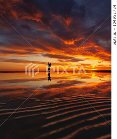 silhouette person against background beautiful sunset sky on ocean, reflection rays sun in water silhouette person against background beautiful sunset sky on ocean, reflection rays sun in water 104952784