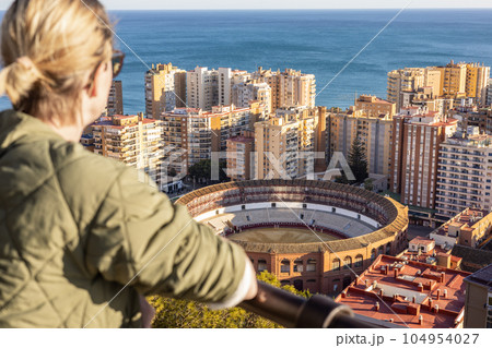 Bolnde female touris enjoying amazing panoramic aerial view of bull ring in Malaga, Spain. 104954027