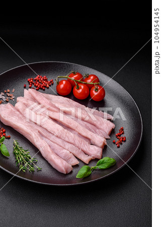 Raw chicken or turkey fillet cut into strips with spices and herbs 104954145