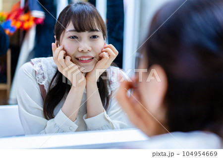 メイクルームで笑顔のチェックをする若い女性 104954669