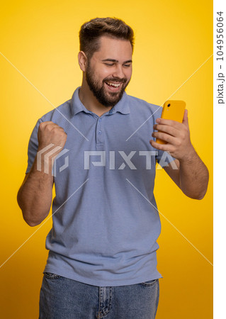 Happy excited winner young man use smartphone say wow yes found out great big win good news lottery Happy excited winner young man use smartphone say wow yes found out great big win good news lottery 104956064
