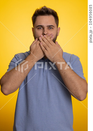 Frightened scared man closing his mouth with hand, gestures no, refusing to tell terrible secret Frightened scared man closing his mouth with hand, gestures no, refusing to tell terrible secret 104956085