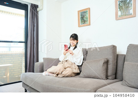 スマホを使用する私服の若い女性 リビング スマホを使用する私服の若い女性 リビング 104958410