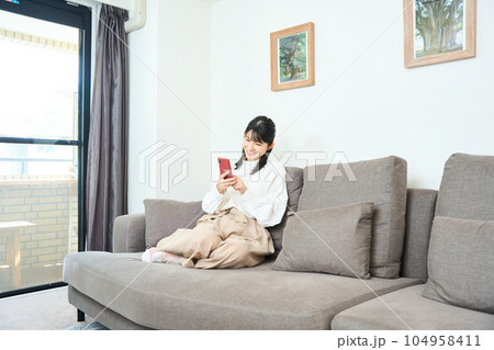 スマホを使用する私服の若い女性　リビング　 104958411