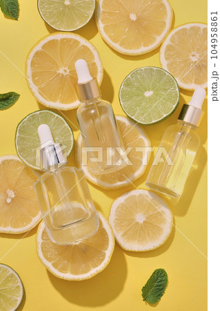 Lime and lemon slices are scattered over yellow background with three unlabeled dropper bottles placed on. Template for facial serum product promotion Lime and lemon slices are scattered over yellow background with three unlabeled dropper bottles placed on. Template for facial serum product promotion 104958861