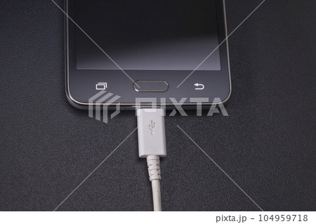 black smartphone on black background with white cable black smartphone on black background with white cable 104959718