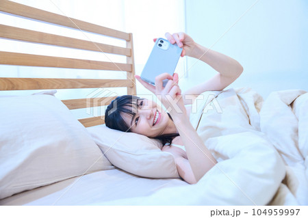 ベッドでスマホを使う女性 104959997