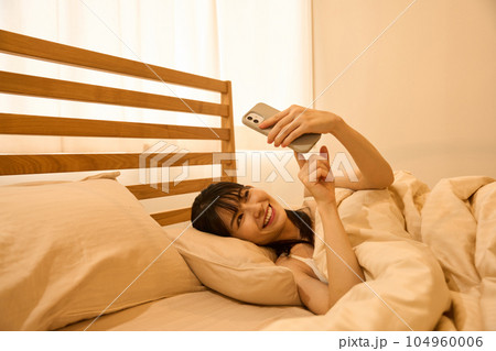 ベッドでスマホを使う女性 ベッドでスマホを使う女性 104960006