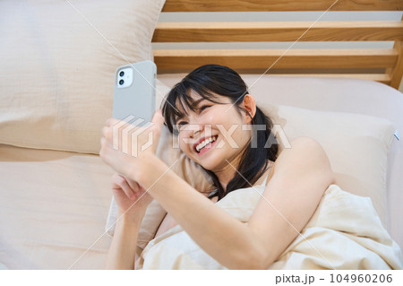 ベッドでスマホを使う女性 104960206
