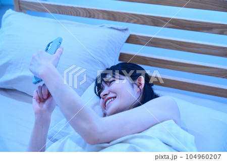 ベッドでスマホを使う女性 104960207