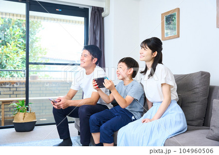 ソファーに座りゲームを楽しむ親子　 104960506