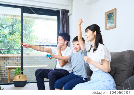 ソファーに座りゲームを楽しむ親子　 104960507