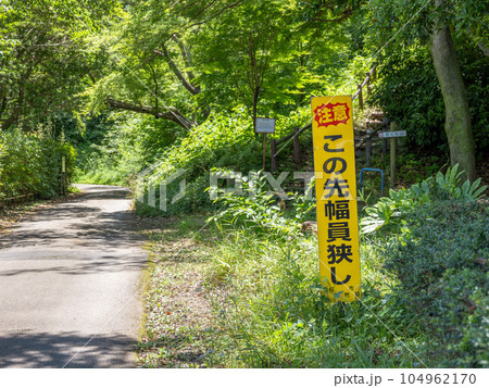 すれ違いが困難な細い道に設置された注意の看板【この先幅員狭し】 すれ違いが困難な細い道に設置された注意の看板【この先幅員狭し】 104962170