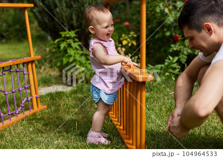 Dad with little daughter collects home sports complex outdoor. 104964533