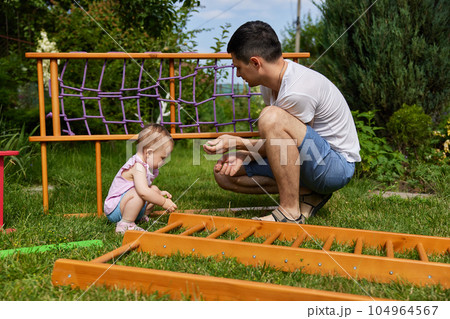 Dad with little daughter collects home sports complex outdoor. 104964567