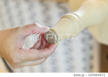 Woman sticking floor care pad at sofa leg 104964672