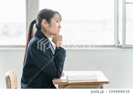 学校の教室で数学の教科書・参考書を見て悩みながら勉強する女子高校生・中学生の生徒（困る・難しい） 104966616