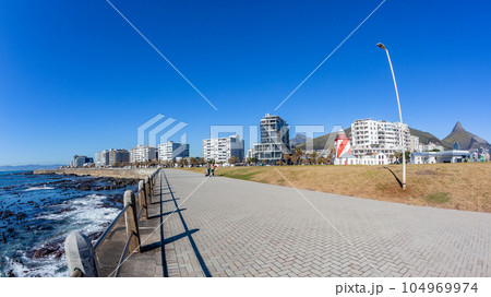 Cape-Town Sea-Point atlantic walking promenade front of buildings and table mountain and lions head on a blue summers day. 104969974