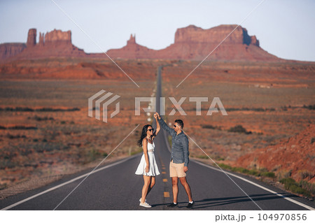 Happy couple on the famous road to Monument Valley in Utah in their trip on Canyon in USA. Scenic highway in Monument Valley Tribal Park in Utah. Happy couple on the famous road to Monument Valley in Utah in their trip on Canyon in USA. Scenic highway in Monument Valley Tribal Park in Utah. 104970856
