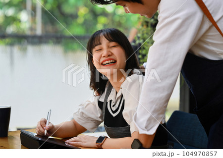 Happy young couple using digital tablet and working together at their coffee shop. Small business management concept Happy young couple using digital tablet and working together at their coffee shop. Small business management concept 104970857