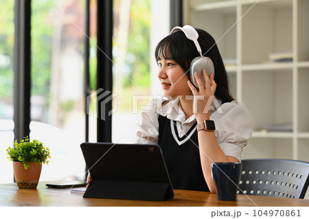 Thoughtful asian student woman listening music in wireless headphones and looking away. People, technology and lifestyle concept Thoughtful asian student woman listening music in wireless headphones and looking away. People, technology and lifestyle concept 104970861
