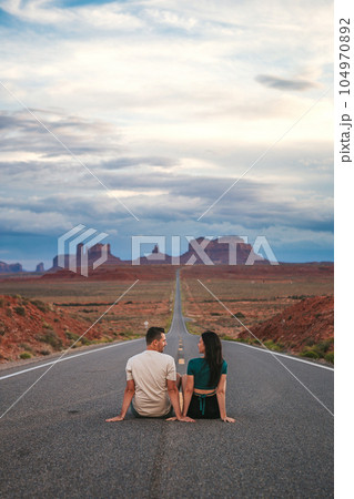 Happy couple on the famous road to Monument Valley in Utah. Amazing view of the Monument valley. 104970892