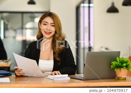 Portrait of asian woman investor using laptop and working on financial document in office Portrait of asian woman investor using laptop and working on financial document in office 104970917